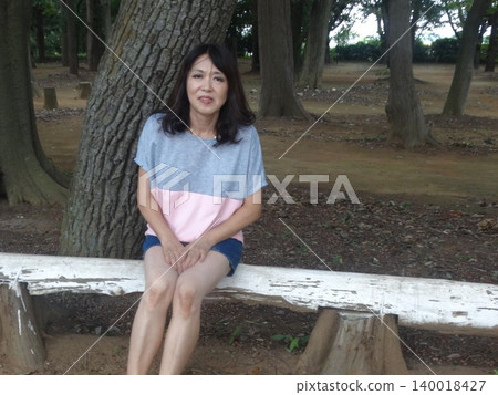 一位身著夏裝的女子坐在樹蔭下 一位身著夏裝的女子坐在樹蔭下 140018427