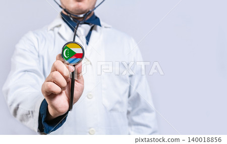Hands doctor holding stethoscope with Comoros flag. Comoros health and care concept Hands doctor holding stethoscope with Comoros flag. Comoros health and care concept 140018856