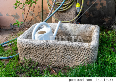 Green Watering Cans in Rustic Garden Stone Container Outdoors Green Watering Cans in Rustic Garden Stone Container Outdoors 140018933