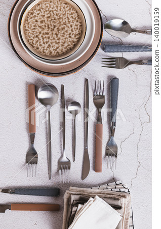Forks, spoons, knives, plates and napkins on the table top and vertical view 140019159
