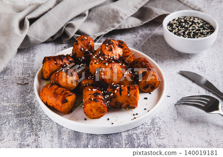 Spicy sausage bites with garlic and sesame seeds on a plate on the table Spicy sausage bites with garlic and sesame seeds on a plate on the table 140019181
