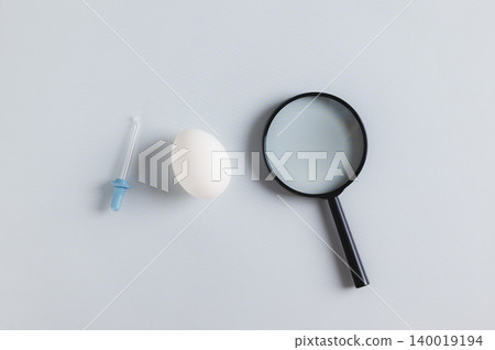 Close up of salmonella concept, chicken egg, pipette and magnifying glass on the table top view Close up of salmonella concept, chicken egg, pipette and magnifying glass on the table top view 140019194