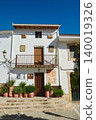 White house with balcony and potted plants in a sunny Spanish village 140019326