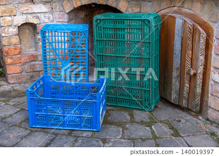 two green and one blue plastic crates in front of a brick wall two green and one blue plastic crates in front of a brick wall 140019397