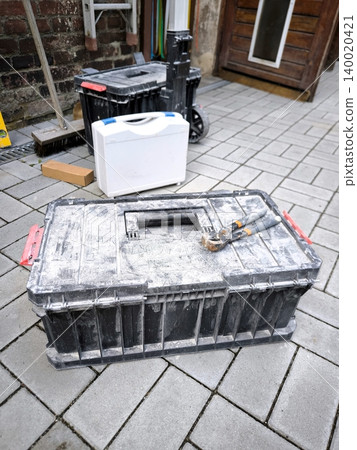 A black plastic tool box with pliers on the lid in the yard. A black plastic tool box with pliers on the lid in the yard. 140020421