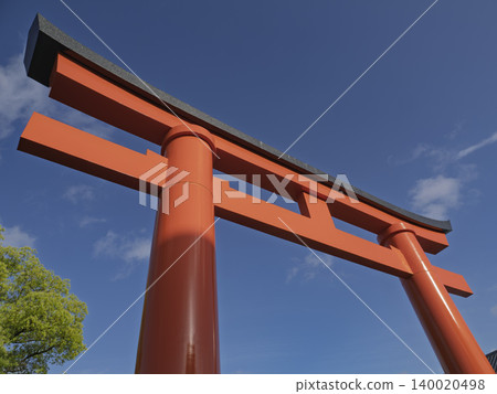 A vibrant vermilion torii gate stands out dramatically against the blue sky. A vibrant vermilion torii gate stands out dramatically against the blue sky. 140020498