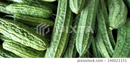 Close-up photo of fresh green vegetables in the form of bitter melon and chayote neatly arranged in a traditional market. Close-up photo of fresh green vegetables in the form of bitter melon and chayote neatly arranged in a traditional market. 140021151