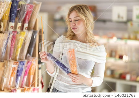 Happy girl holding essential oil sticks and deciding whether to buy them or not 140021762