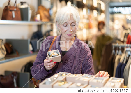 Attentive mature woman choosing wrist watch in accessories store Attentive mature woman choosing wrist watch in accessories store 140021817