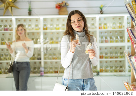 Young woman choosing perfume in store Young woman choosing perfume in store 140021908