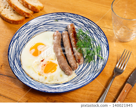 Fried eggs served with sausages on plate Fried eggs served with sausages on plate 140021945