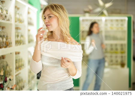 Smiling woman looking perfume for in perfume modern beauty shop Smiling woman looking perfume for in perfume modern beauty shop 140021975