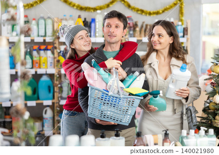 Couple man and woman with daughter chooses household chemicals in decorated store 140021980