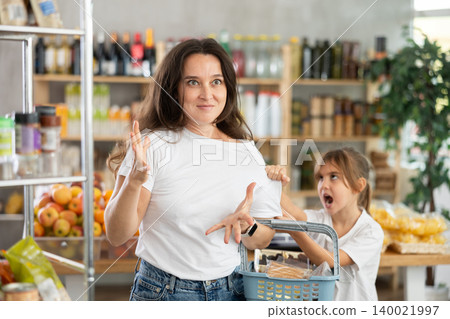 Capricious daughter screams and demands to buy sweets at the store. Mom is shocked by the naughty child Capricious daughter screams and demands to buy sweets at the store. Mom is shocked by the naughty child 140021997