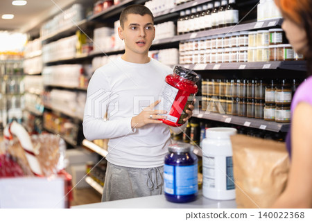 Guy communicates with seller near cash register, sport nutrition shop Guy communicates with seller near cash register, sport nutrition shop 140022368
