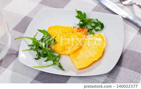 Two pieces of fried omelet decorated with arugula leaves are served for breakfast in restaurant Two pieces of fried omelet decorated with arugula leaves are served for breakfast in restaurant 140022377