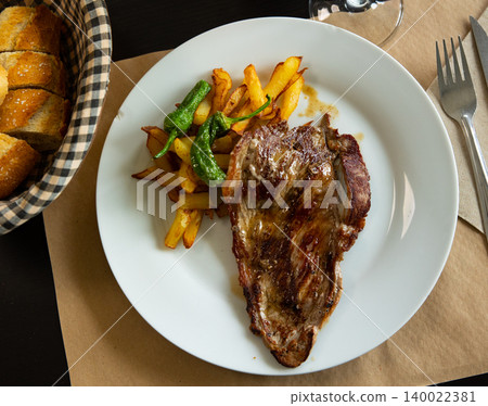 Fried beef served with potatoes and peppers Fried beef served with potatoes and peppers 140022381