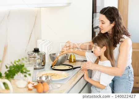 Mom and her daughter fry pancakes Mom and her daughter fry pancakes 140022427