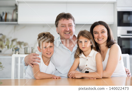 Happy family with two children sitting at table at home Happy family with two children sitting at table at home 140022473