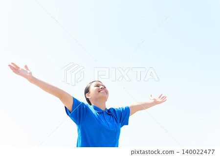 A foreign female caregiver raises both hands to the blue sky. 140022477