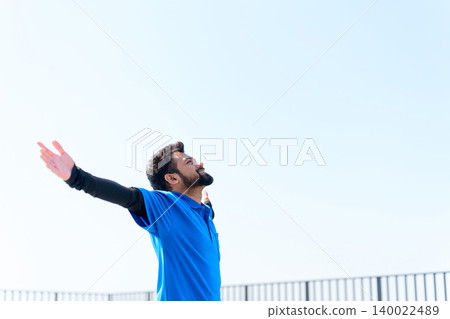 A foreign male caregiver raises both hands to the blue sky. A foreign male caregiver raises both hands to the blue sky. 140022489