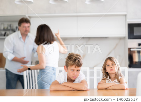 Kids feels upset while parents quarrel at background. Little girl and boy frustrated with psychological problem caused by mom and dad arguing, family conflicts or divorce impact on child concept 140022517