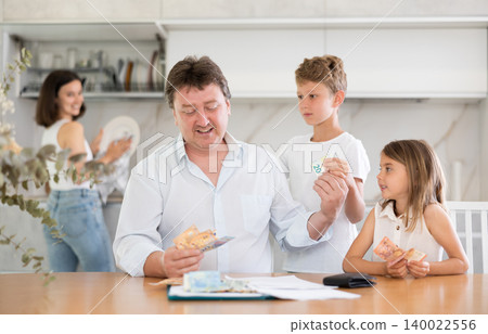 Happy father giving money to children in the kitchen 140022556
