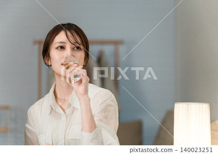 A woman drinking champagne or sparkling wine as an evening drink. A woman drinking champagne or sparkling wine as an evening drink. 140023251