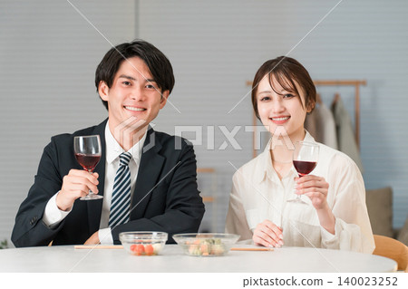 A couple enjoying wine at the dining table in the evening. A couple enjoying wine at the dining table in the evening. 140023252