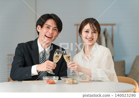 一對笑容滿面的夫婦在家中的餐桌旁享用香檳或氣泡酒。 一對笑容滿面的夫婦在家中的餐桌旁享用香檳或氣泡酒。 140023290