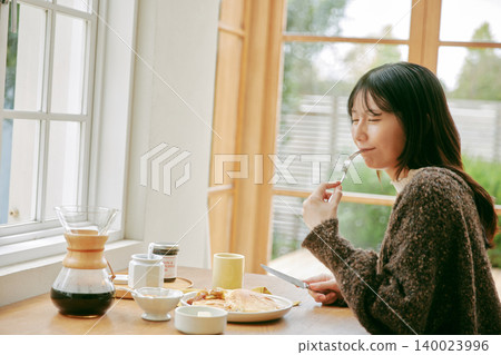 A woman living alone enjoys making her own breakfast. A woman living alone enjoys making her own breakfast. 140023996