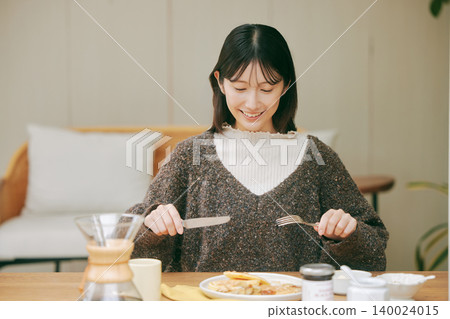 A woman living alone enjoys making her own breakfast. A woman living alone enjoys making her own breakfast. 140024015