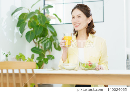 一位中年日本女性正在喝含有維生素C的柳橙汁。 一位中年日本女性正在喝含有維生素C的柳橙汁。 140024065
