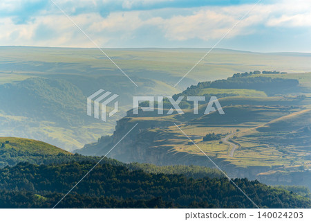 Layers of green mountains and hills in the haze during sunset. Panoramic View of Green hills and Meadow. Layers of green mountains and hills in the haze during sunset. Panoramic View of Green hills and Meadow. 140024203