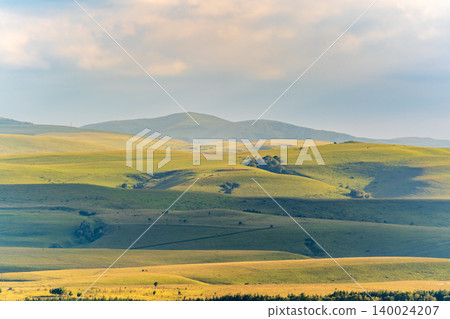 Layers of green mountains and hills in the haze during sunset. Panoramic View of Green hills and Meadow. 140024207