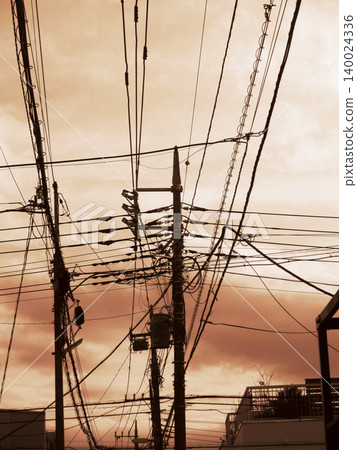 A view of telephone poles in the city at dusk against the twilight sky. A view of telephone poles in the city at dusk against the twilight sky. 140024336
