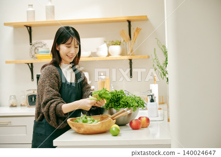 一位女士正在用新鮮蔬菜做飯 一位女士正在用新鮮蔬菜做飯 140024647