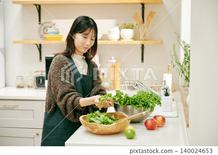 一位女士正在用新鮮蔬菜做飯 一位女士正在用新鮮蔬菜做飯 140024653