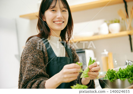 一位女士正在用新鮮蔬菜做飯 一位女士正在用新鮮蔬菜做飯 140024655