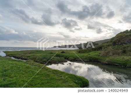 A shallow, rippling coastline and a grassland with puddles that connect to the adjacent sea. A shallow, rippling coastline and a grassland with puddles that connect to the adjacent sea. 140024949