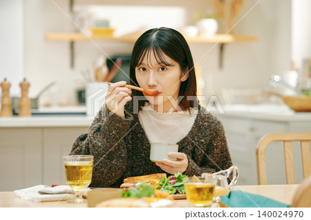 A woman eating her meal with apparent enjoyment. A woman eating her meal with apparent enjoyment. 140024970