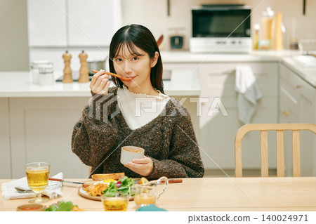 A woman eating her meal with apparent enjoyment. A woman eating her meal with apparent enjoyment. 140024971