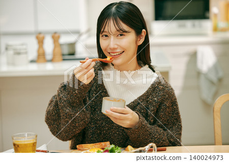 A woman eating her meal with apparent enjoyment. A woman eating her meal with apparent enjoyment. 140024973