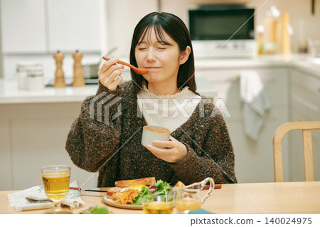 A woman eating her meal with apparent enjoyment. A woman eating her meal with apparent enjoyment. 140024975