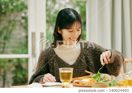 一位女士正在津津有味地用餐。 一位女士正在津津有味地用餐。 140024993