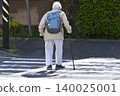 An elderly man with a cane (wearing a mask) crosses a pedestrian crossing in Yokohama, Japan. A dark shadow sways across the crosswalk... What is life...? 140025001