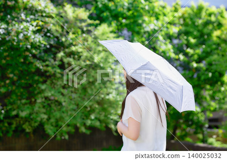 一位二十多歲的女子撐著陽傘。 一位二十多歲的女子撐著陽傘。 140025032