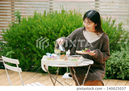 一位女士在花園裡吃墨西哥捲餅 一位女士在花園裡吃墨西哥捲餅 140025037