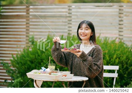 一位女士在花園裡吃墨西哥捲餅 一位女士在花園裡吃墨西哥捲餅 140025042