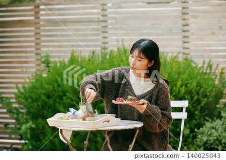 一位女士在花園裡吃墨西哥捲餅 140025043